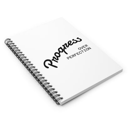 Progress over perfection spiral notebook on desk top view, motivational planner for productivity and personal growth
