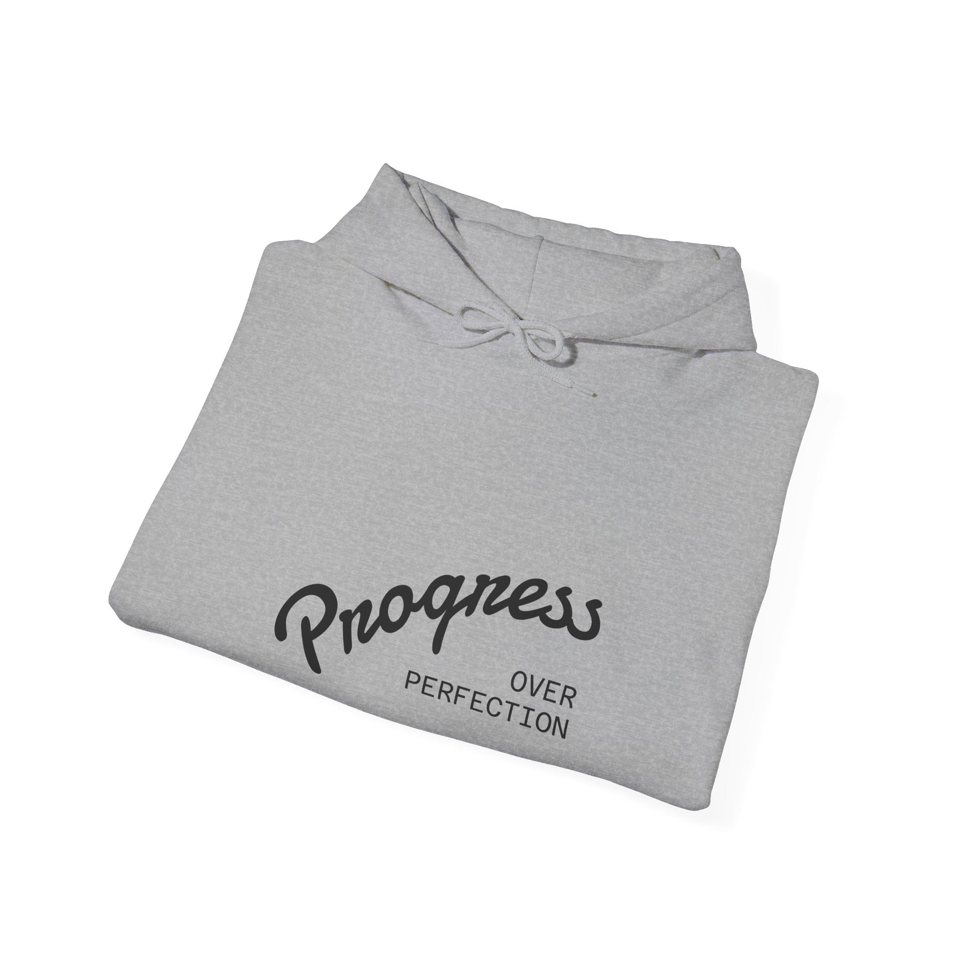 Folded gray hoodie with 'Progress Over Perfection' text on a white background