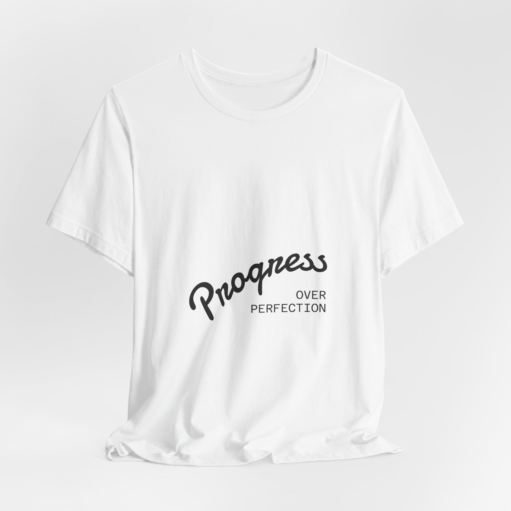 White t-shirt with 'Progress Over Perfection' text on a light gray background