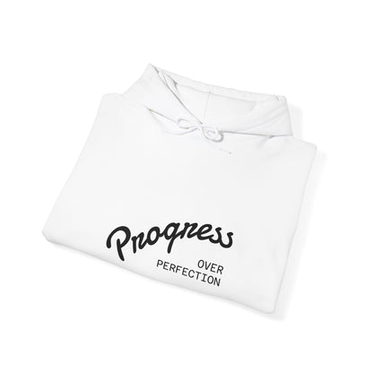Folded white hoodie with 'Progress Over Perfection' text on a white background