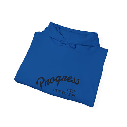 Folded blue hoodie with 'Progress Over Perfection' text on a white background