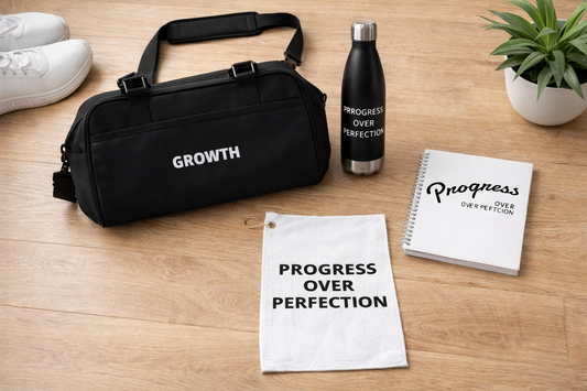 Black duffel bag, water bottle, towel, and notebook on a wooden surface with 'Growth' and 'Progress Over Perfection' text.