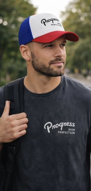 Man wearing Progress Over Perfection red white blue trucker hat outdoors motivational headwear