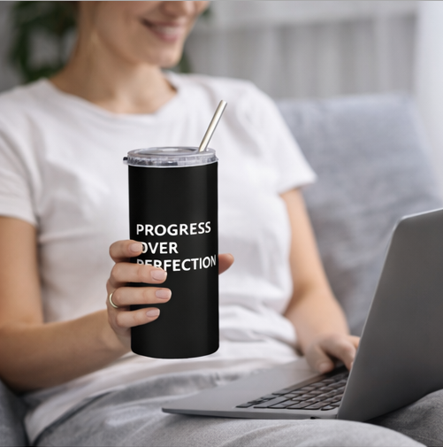 Woman holding Progress Over Perfection black tumbler with straw working on laptop motivational drinkware
