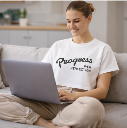 Woman wearing Progress Over Perfection crop top working on laptop motivational workwear