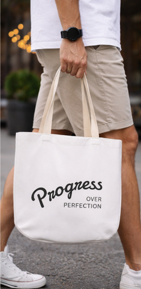 Progress Over Perfection motivational quote tote bag held by a man in casual outfit

