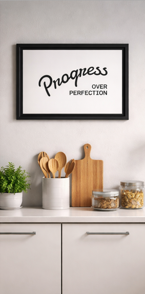 Progress Over Perfection framed print on wall above kitchen counter with plants