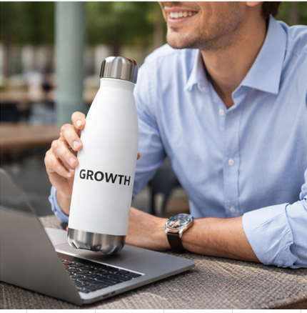 Professional using growth motivational water bottle at desk workspace, white insulated bottle for office hydration and productivity
