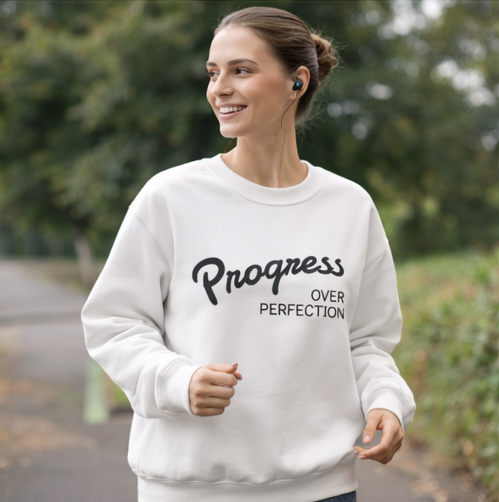 Woman wearing progress over perfection white crewneck during outdoor walk, motivational fitness apparel for active lifestyle
