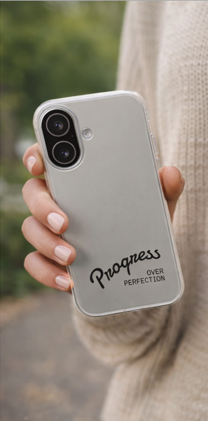 Hand holding progress over perfection white phone case outdoors, motivational smartphone case with black script typography
