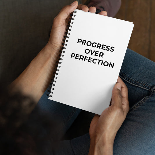 Hands holding Progress Over Perfection spiral notebook motivational journal 140 pages