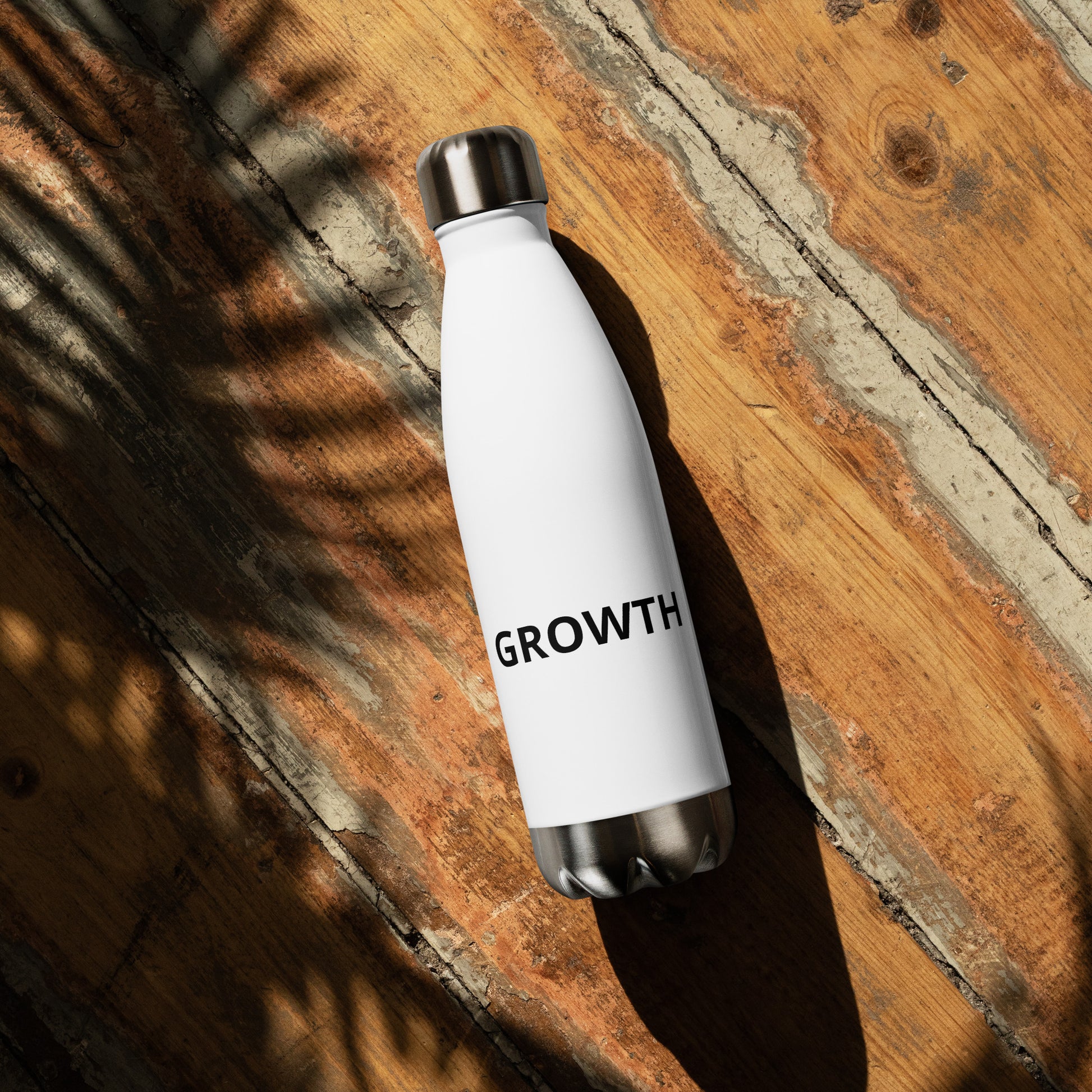 Growth motivational water bottle close-up on rustic wood, white insulated stainless steel bottle with motivational text

