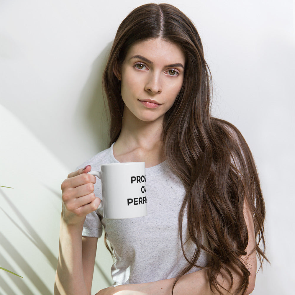 Young woman holding progress over perfection motivational coffee mug, white ceramic cup for personal growth and mindset development

