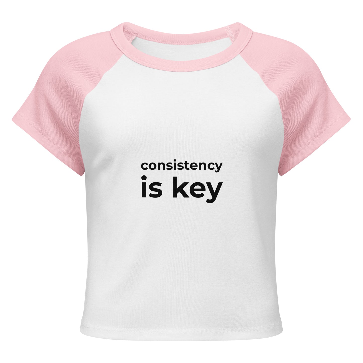 Consistency is key pink and white raglan t-shirt front view, motivational women's apparel with bold black text
